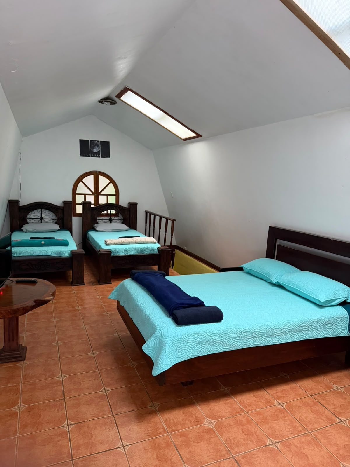 A bedroom with two beds, a wooden headboard, a small table, and a ceiling light.