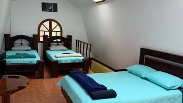 A bedroom with two beds, a wooden headboard, a small table, and a ceiling light.