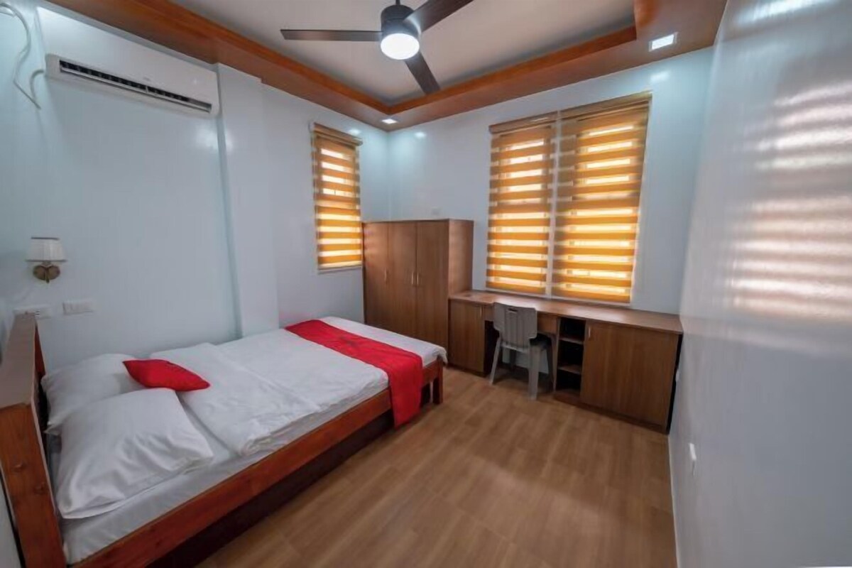 A bedroom with a bed, desk, and wardrobe.