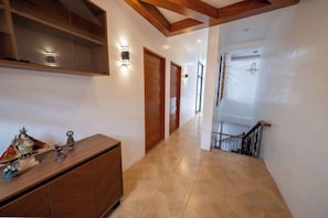A hallway with a wooden cabinet, wall-mounted lights, and a staircase.