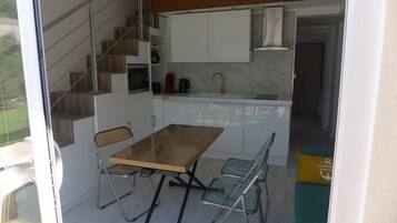 Een compacte keuken met een eettafel en stoelen, een inbouwfornuis en een spoelbak.