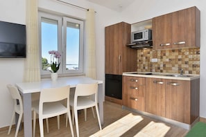 Et moderne køkken med træskabe, en mikroovn og et spiseområde med et hvidt bord og stole.