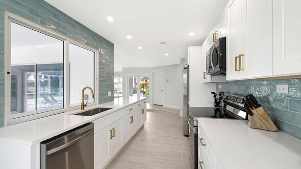 A modern kitchen with white cabinetry, a stainless steel dishwasher, and a built-in oven.