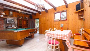 A wooden interior with a pool table, a dining table with chairs, and a kitchen area. - Holiday apartment with washing machine (Pula)