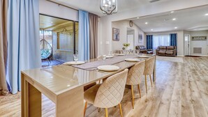 A spacious dining area with a long table, cushioned chairs, and a chandelier. - Relax and recharge Hot Tub,Tesla charger,10 sleeps (Sarasota)