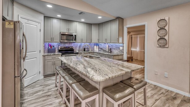 A modern kitchen with a central island, stainless steel appliances, and a backsplash. - Relax and recharge Hot Tub,Tesla charger,10 sleeps (Sarasota)