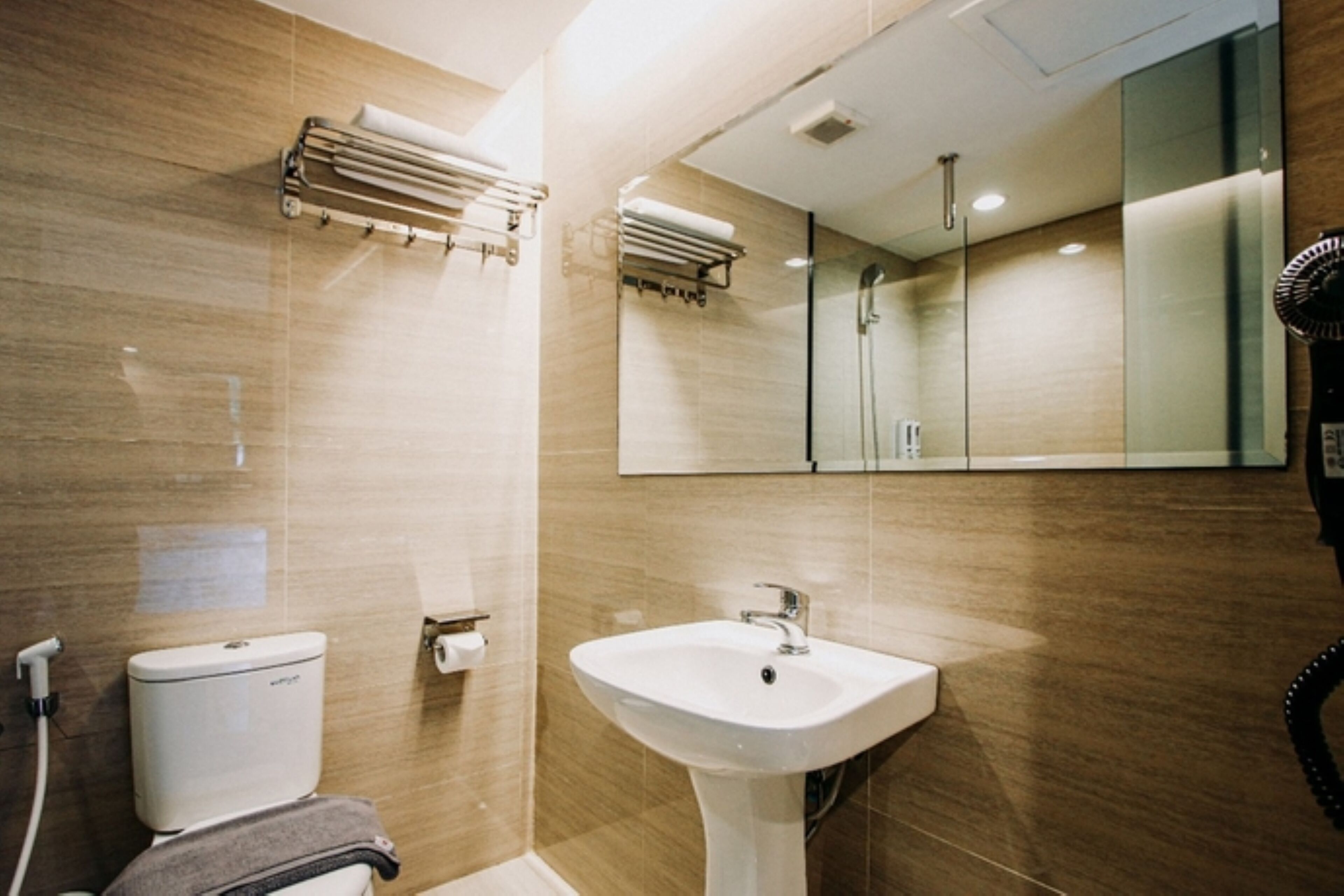 Un baño moderno con inodoro, lavabo, toallero y espejo.