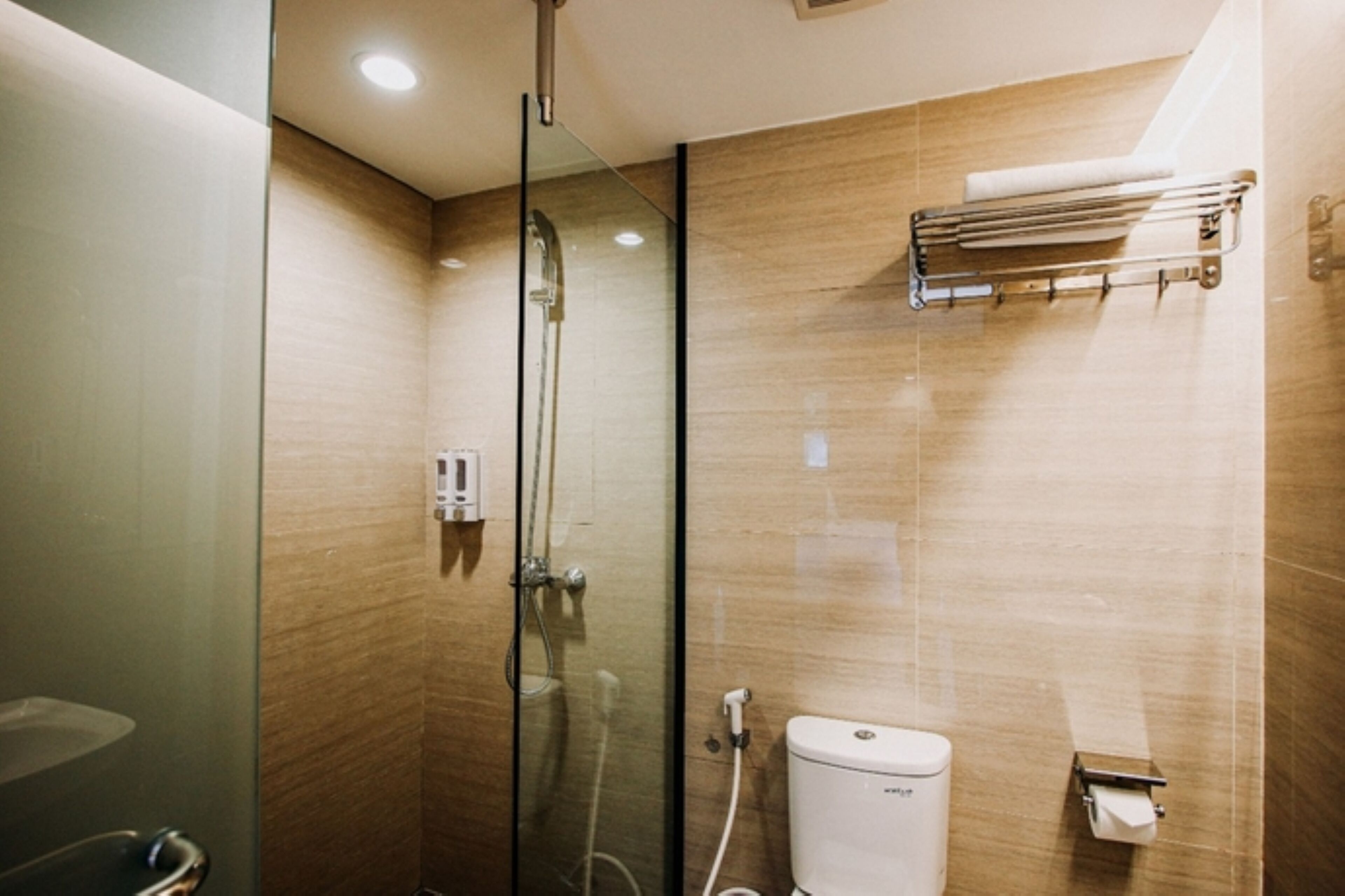 Un baño moderno con cabina de ducha de vidrio, un inodoro y un perchero para toallas.