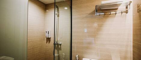 Un baño moderno con cabina de ducha de vidrio, un inodoro y un perchero para toallas.