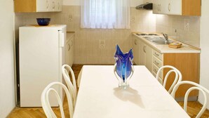 Una cocina con un refrigerador blanco, un lavamanos y una mesa de comedor con sillas.