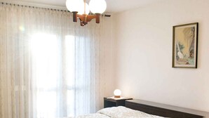 Un dormitorio con una cama grande, una mesita de noche, una lámpara y un cuadro en la pared.