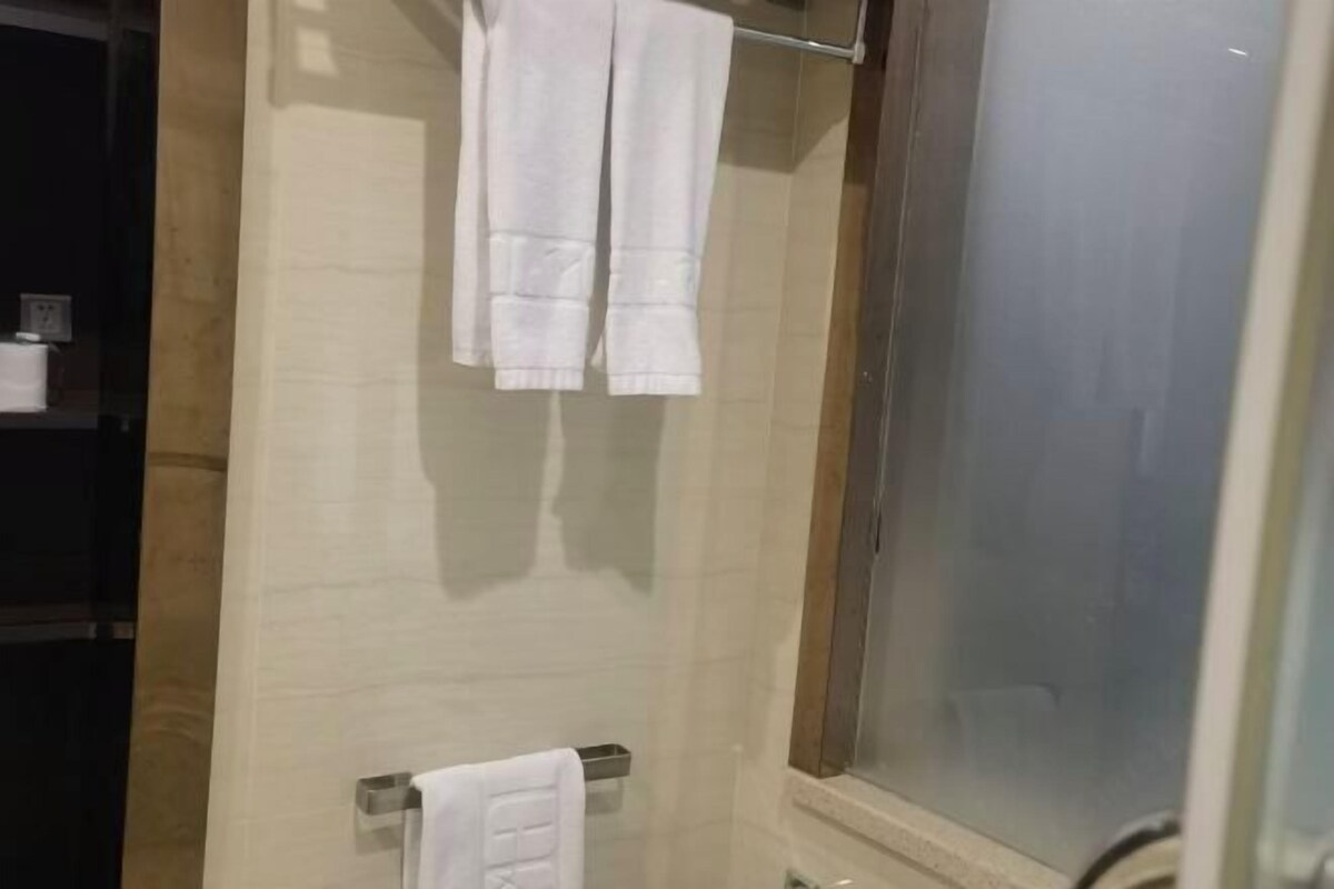A bathroom with a shower, a towel rack, and a glass shower door.