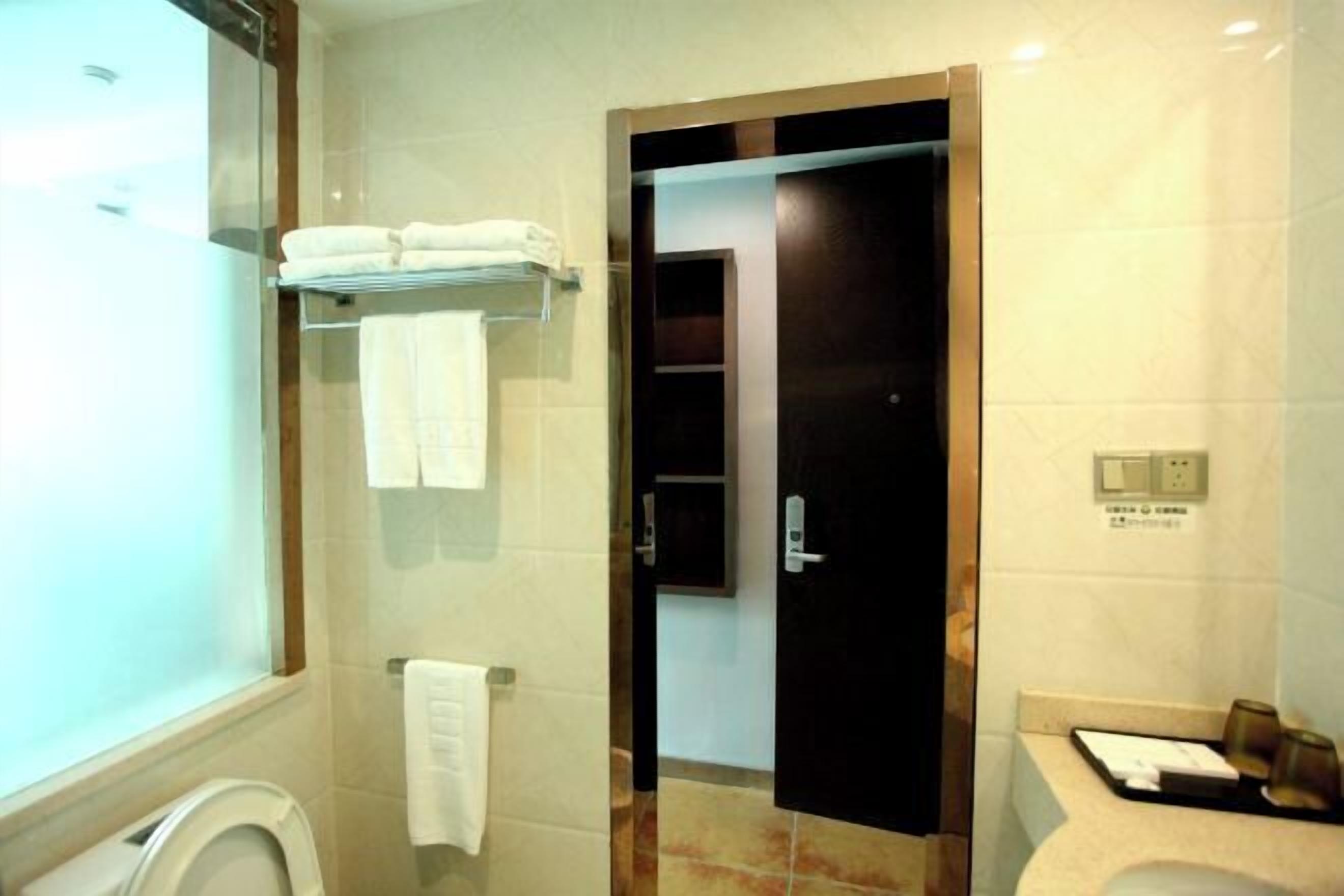 Ein Badezimmer mit Toilette, Handtuchhalter, einer Duschkabine aus Glas und einem Waschbecken mit Spiegel.