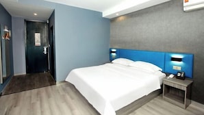 Quarto de hotel moderno com uma cama grande, mesa de cabeceira com telefone e ar condicionado fixado na parede.