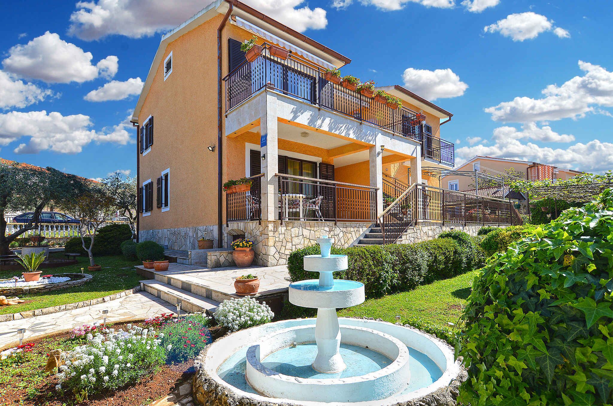 A two-story building with a balcony, a fountain, and a garden.