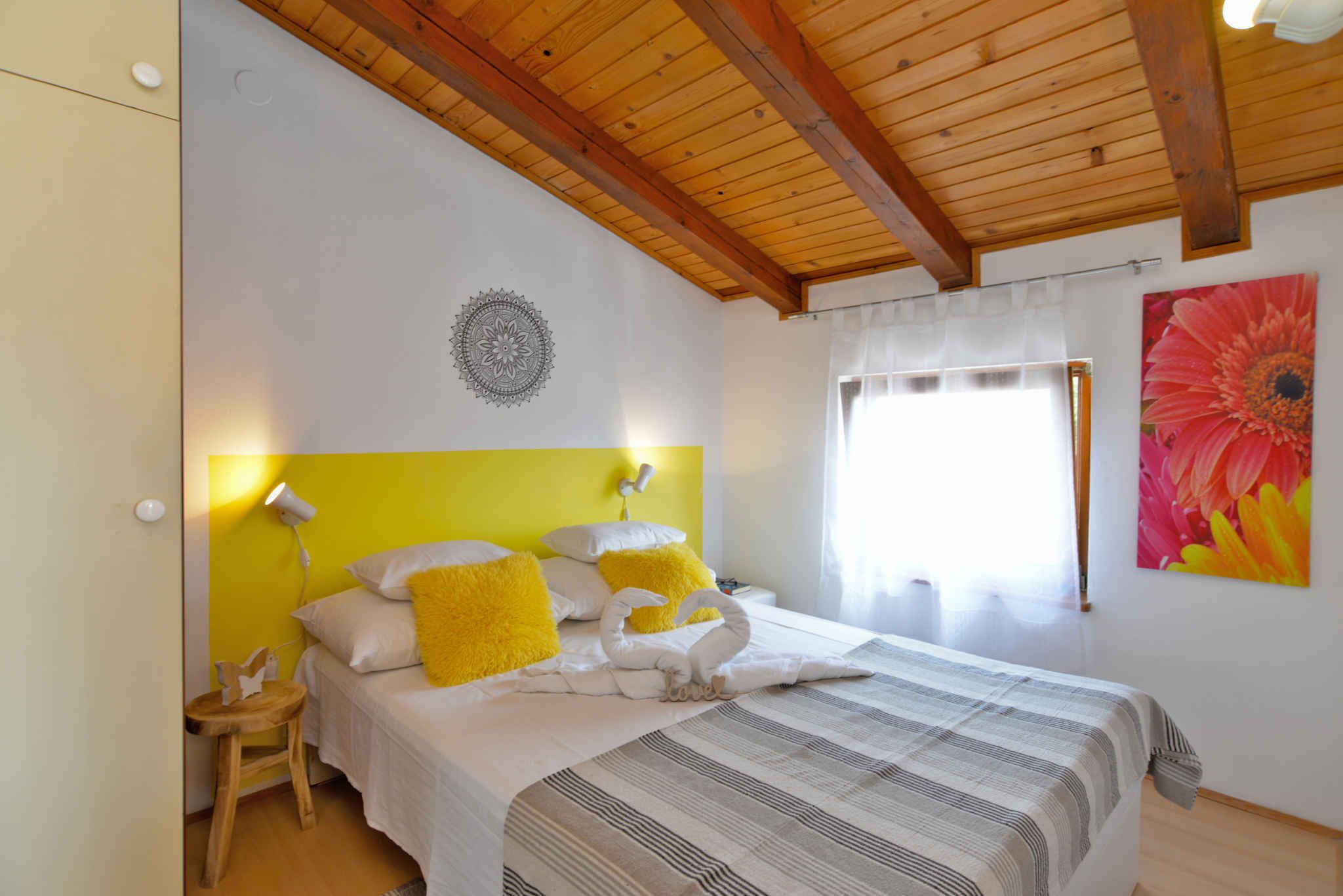 Een slaapkamer met een houten plafond, een bed met gestreept beddengoed, een geel kussen en een muur met een rond ontwerp.