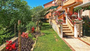 A building with a garden, a staircase, and a fence.