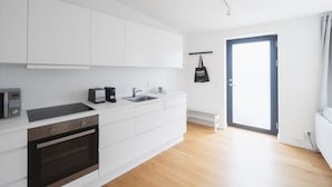 Une cuisine moderne avec des meubles blancs, un four encastré, un four à micro-ondes et un grille-pain.