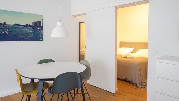 Une chambre compacte comprenant un coin repas, un lit et une vue sur le paysage urbain.