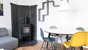 A modern living room with a stone fireplace, a round dining table, and colorful chairs. - Beautiful 2-bed w Large Balcony (Copenhagen)