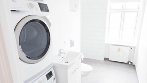 Ein moderner Waschraum mit einer Waschmaschine und einem Trockner, einem Waschbecken und einer Toilette.