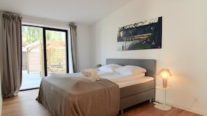 Une chambre à coucher avec un lit, une table de chevet, une lampe et une fenêtre avec des rideaux.