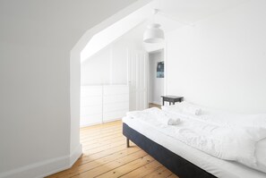 A bedroom with a bed, wooden floor, white walls, and a skylight. - Great 3-bed in Fantastic Location (Copenhagen)