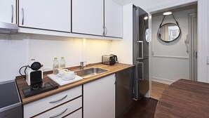 A modern kitchen with white cabinets, a wooden countertop, a sink, a toaster, and a refrigerator. - Nice 1-bed Near Copenhagen Lakes (Copenhagen)