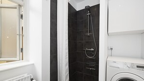A bathroom with a shower, a toilet, and a washing machine. - Nice 1-bed Near Copenhagen Lakes (Copenhagen)