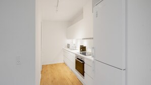 Une cuisine moderne avec des meubles blancs, un four encastré et un four à micro-ondes.