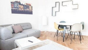Un soggiorno moderno con un divano grigio, un tavolino da caffè bianco e un'area pranzo con sedie.