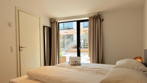 Una habitación de hotel con cama, vistas a un balcón y una puerta.
