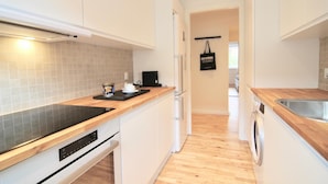 A modern kitchen with white cabinets, a wooden countertop, a built-in oven, and a washing machine. - Lovely 2-bed in Frederiksberg w Balcony - 177 (Frederiksberg)