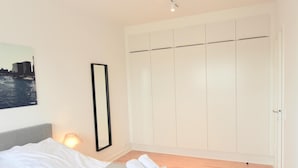 Ett hotellrum med en säng, en sänglampa, en stor garderob och en inramad tavla på väggen.