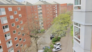 En flervåningsbostadsbyggnad med en fasad av tegel, många fönster och en parkeringsplats med bilar.