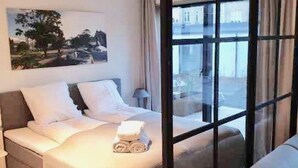 Une chambre à coucher avec un lit, une table de chevet, une fenêtre et une vue sur l’extérieur.