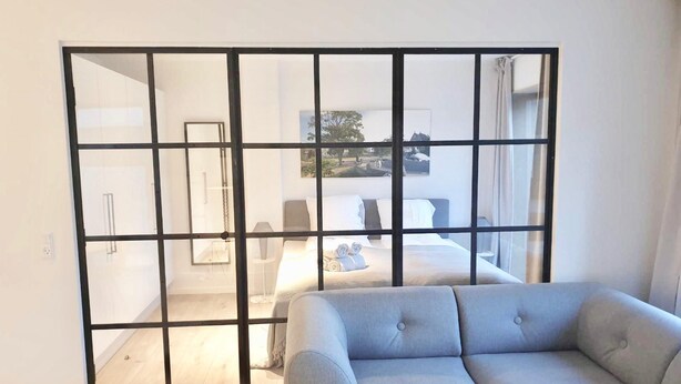 Une chambre moderne dotée d’une grande porte coulissante donnant sur un balcon.