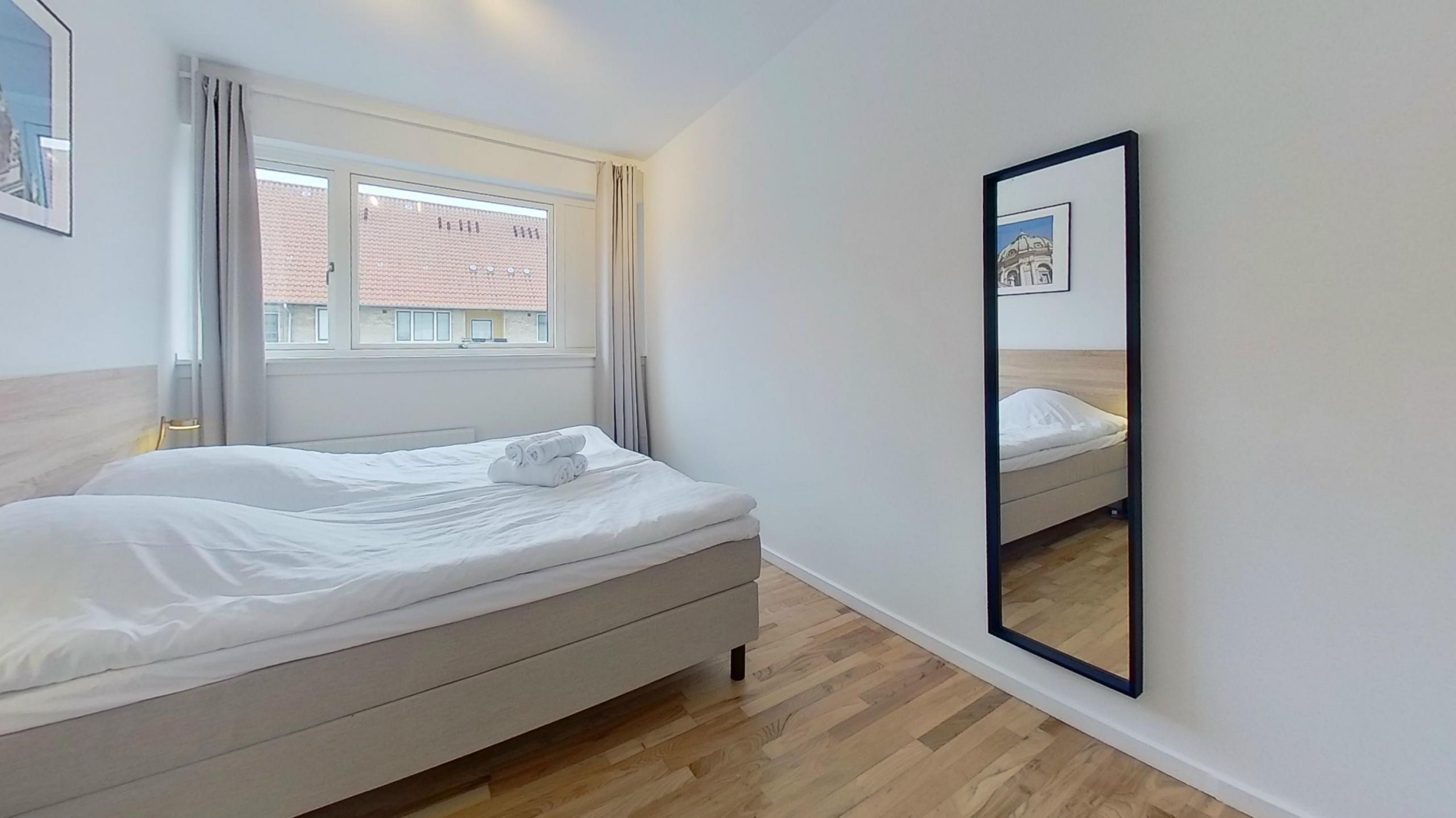 Una habitación de hotel con una cama, una ventana y un espejo.
