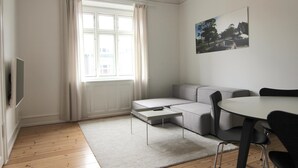 A modern living room with a sofa, a coffee table, and a dining table with chairs. - Beautiful 2-bed in Frederiksberg C W Balcony (Frederiksberg)