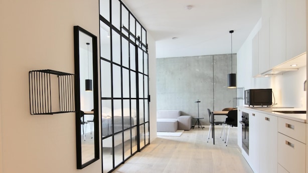 Eine moderne Küche mit weißen Schränken, ein Essbereich mit Tisch und Stühlen sowie ein großes Fenster.
