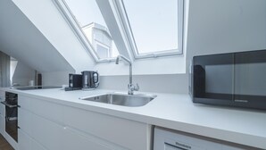 A modern kitchen with a skylight, stainless steel sink, black microwave, and Bosch dishwasher. - Beautiful 1-bed in Peaceful Surroundings (Aarhus)