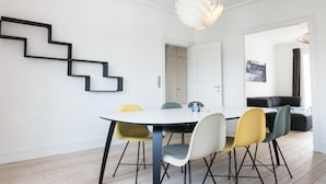 Un'area pranzo moderna con un tavolo bianco, sedie colorate e un'originale decorazione geometrica nera a parete.