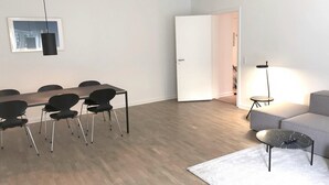 Ein modernes Wohnzimmer mit Essbereich, einer Couch, einem Couchtisch und einer Lampe.