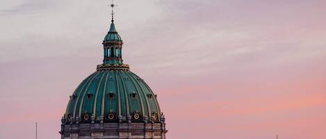 A large domed building with a spire, surrounded by rooftops and other structures.