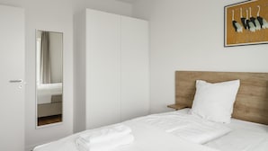 A hotel room with a bed, a wooden headboard, a white wall, and a framed picture of birds. - Top-class 1-bedroom Apartment in Odense (Odense)
