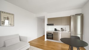 A modern living room with a sofa, a dining table, and a kitchen area with stainless steel appliances. - Top-class 1-bedroom Apartment in Odense (Odense)