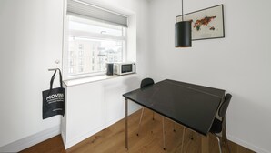 A modern, minimalistic room with a large window, a black table, and a black chair.