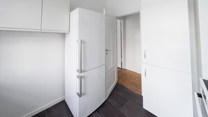 Une cuisine moderne avec des meubles blancs, un réfrigérateur et un plancher en bois.