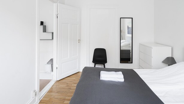 Une chambre d’hôtel avec un lit, une chaise, une commode et un miroir.
