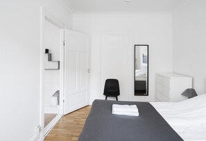 Una camera d'albergo con un letto, una sedia, una cassettiera e uno specchio.